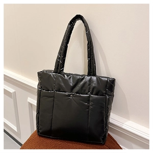Sac fourre-tout matelassé noir brillant avec poche frontale à bouton sur un tabouret