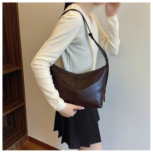 Detail view of the vintage brown faux leather texture and metallic zipper of the crescent bag