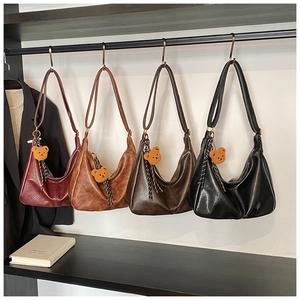 Detail view of four vintage hobo bags in assorted colors with bear charms and straps