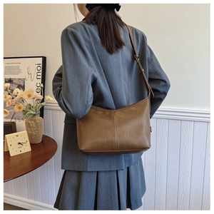 Caramel brown vintage textured leather hobo bag worn by model in a minimalist setting