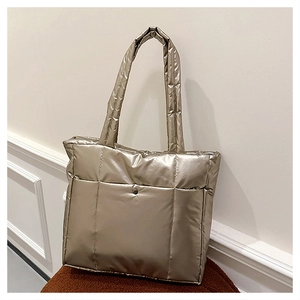 Détail du rembourrage vertical et de la finition dorée champagne sur un sac cabas