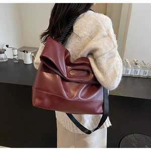 Detail view of large burgundy tote bag with woven handles and a wide shoulder strap