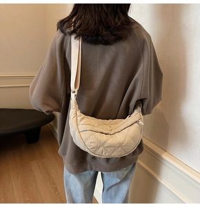 Rear view of a model wearing the cream quilted crescent bag with adjustable strap