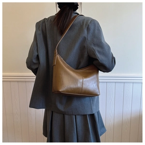 Brown faux leather crescent bag worn by model in a grey suit for a stylish look