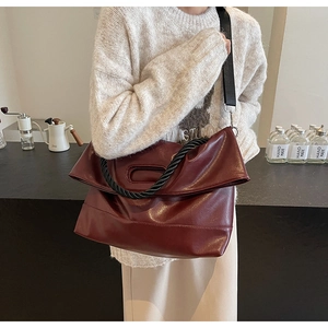 Macro view of burgundy PU leather tote with black woven handles and broad strap