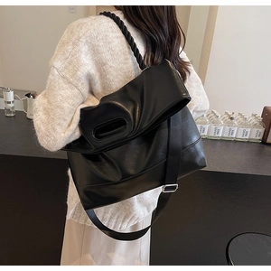 Detail of black leather tote bag with braided handle and adjustable wide nylon shoulder strap