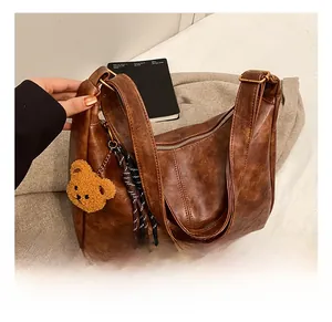 Detail view of brown vintage PU leather bag with teddy bear charm and striped fringe
