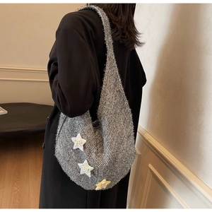 Detailansicht einer grauen Tweed-Einkaufstasche mit Sternanhängern an einem Model