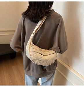 Close-up of beige quilted crossbody dumpling bag featuring rhombus pattern and wide strap