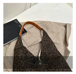 Detail showing leopard print fabric texture and brown leather handle on a tote bag