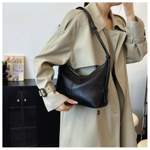Detail of black crescent shoulder bag with pleated faux leather texture and adjustable strap