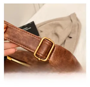 Detailed close-up of brown leather strap with adjustable bronze metal buckle and stitching