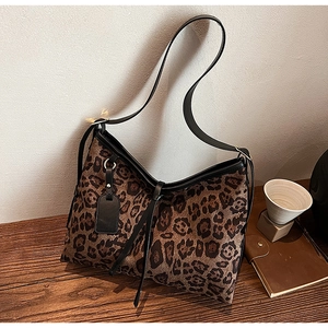 Détail du sac léopard avec lanières en cuir noir et étiquette décorative chic