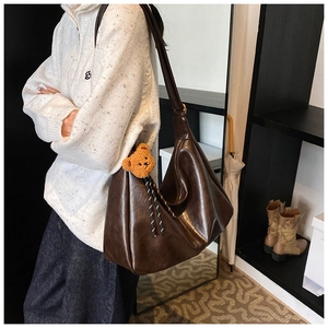 Detail of dark brown tote bag with glossy finish and cute brown bear pendant accessory