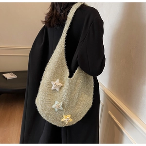 Detail der Stricktasche mit 3D-Sternen und Schleifen vor einem schwarzen Blazer