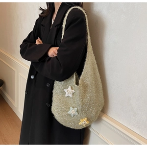 Detail der glitzernden Stricktasche mit farbigen Stern-Aufnähern auf glänzendem Stoff