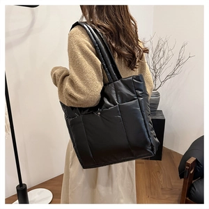 Vue arrière d'un mannequin portant un grand sac cabas noir matelassé en intérieur chic