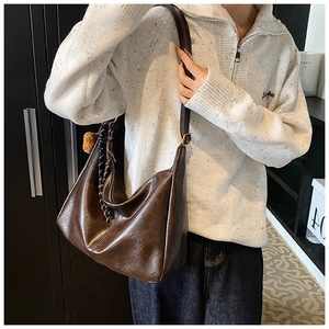 Macro detail of dark brown faux leather bag with woven knot and plush ball accessory
