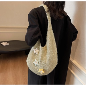 Detail der glitzernden grünen Stricktasche mit Plüschsternen auf schwarzem Blazer