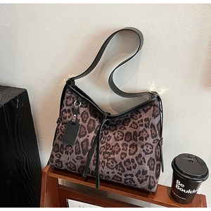 Détail du cabas léopard avec bordures en cuir noir et charm décoratif à pampilles