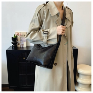 Detail of black wrinkled patent leather texture on a minimalist crescent underarm bag