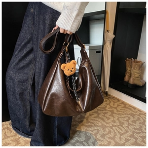 Close-up of retro dark brown oil wax leather hobo bag featuring a cute teddy bear charm