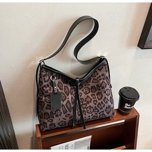 Détail du sac cabas à imprimé léopard avec bandoulière et étiquette en cuir noir