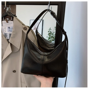 Detailed view of black crescent shoulder bag with textured faux leather and zip closure