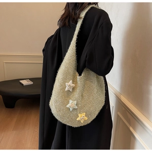 Detail der hellgrünen Strick-Hobo-Tasche mit Glitzergarn und 3D-Stern-Anhängern am Model