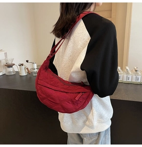 Detail of red quilted dumpling bag with adjustable shoulder strap and padded texture
