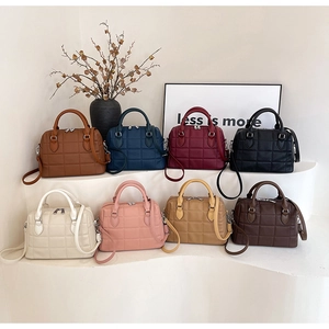 Quilted tote bags in eight colors displayed on minimalist white stands with strap details