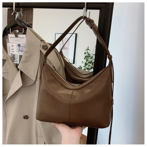 Detail of dark brown faux leather hobo bag with vertical stitching and zip closure