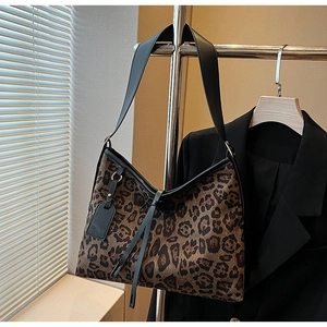 Gros plan du sac cabas léopard avec bandoulières en cuir noir et pompons