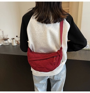 Detail of red quilted dumpling bag showing the rhombus stitching and wide strap