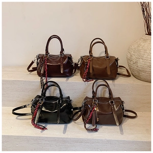 Quatre sacs Boston en cuir ciré présentés sur des marches avec un décor élégant
