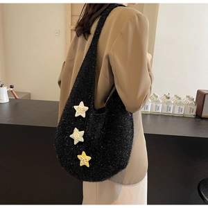 Detail der schwarzen flauschigen Schultertasche mit bunten gestrickten Sternanhängern