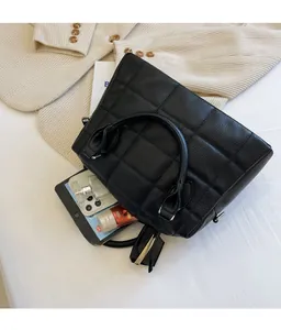 Detailed view of black quilted tote bag with office essentials showing its large capacity