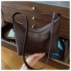 Detail shot of the vintage dark brown leather texture and silver zipper on the shoulder bag