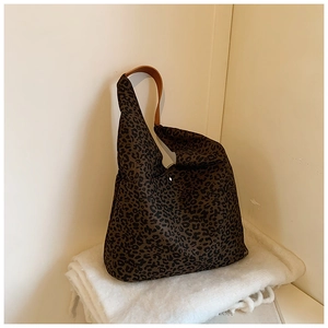 Close-up of leopard print tote bag with brown leather handles on white soft cushions