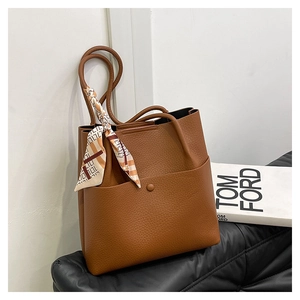 Close-up of brown litchi leather bucket bag featuring decorative silk scarf and front pocket