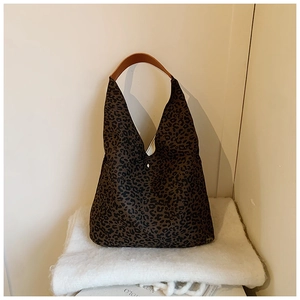 Close-up of leopard print shoulder bag on white knit blanket showing texture and strap