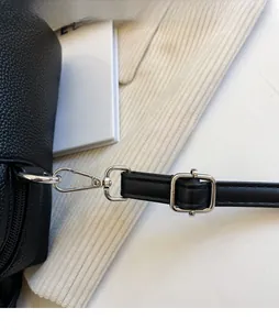 Detail of adjustable litchi grain leather strap with polished silver buckle on tote bag