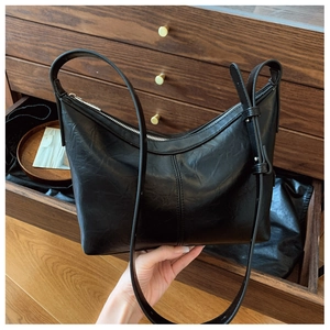 Close-up of black leather hobo bag showing retro wrinkled texture and silver zipper detail