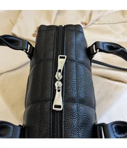 Top detail of black shell tote bag featuring quilted pattern and dual metal zippers