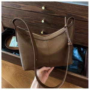 Macro view of textured brown leather hobo bag with zipper closure and adjustable strap