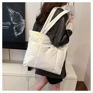Vue latérale d'un sac cabas matelassé blanc avec larges bretelles porté par un modèle