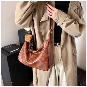 Detailed macro view of vintage brown leather crescent bag with cute plush bear charm