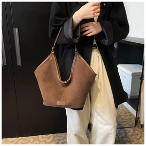 Detail einer großen braunen Shopper-Tasche mit V-Ausschnitt und Markenlogo auf der Unterseite