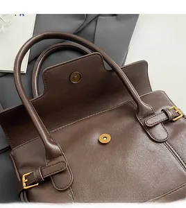 Detail of dark brown retro leather handbag featuring magnetic closure and golden buckle