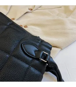Detail of black lychee grain leather tote with quilted diamond stitching and silver hardware